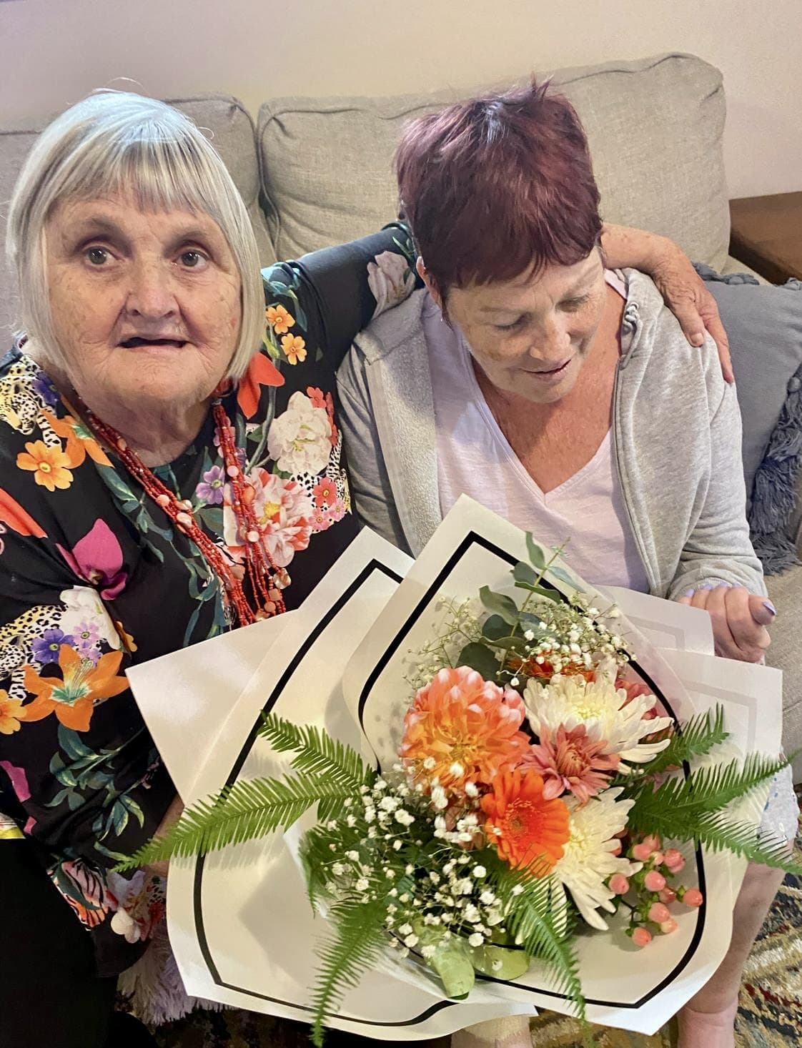 Two women sharing a warm moment together with a bouquet of flowers